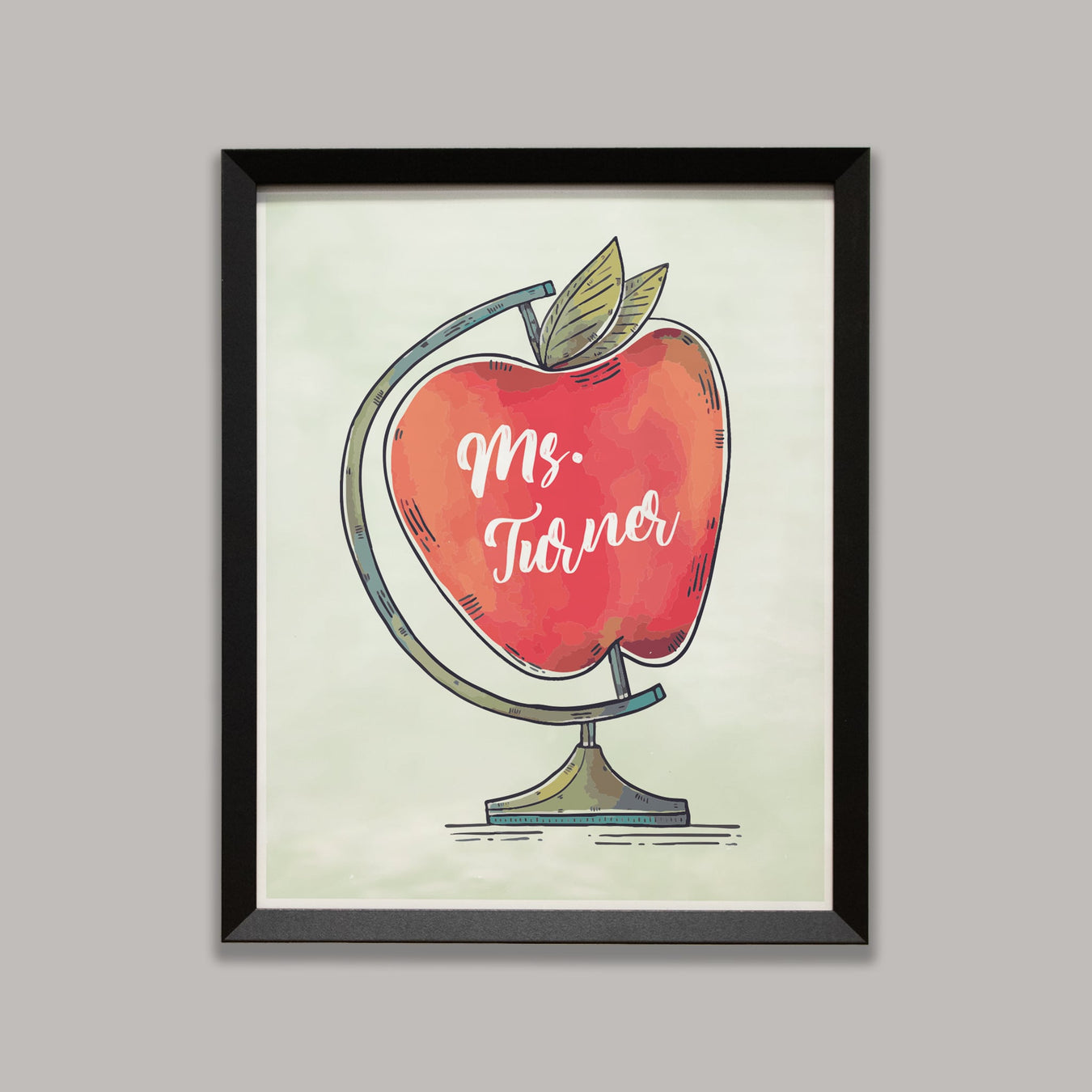 Framed artwork of a red apple with teacher's name on a light gray background