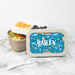 Personalized lunch box with a blue sea-themed design, containing snacks on a marble surface.