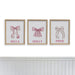 Three framed prints with pink bows and names on a white wall.