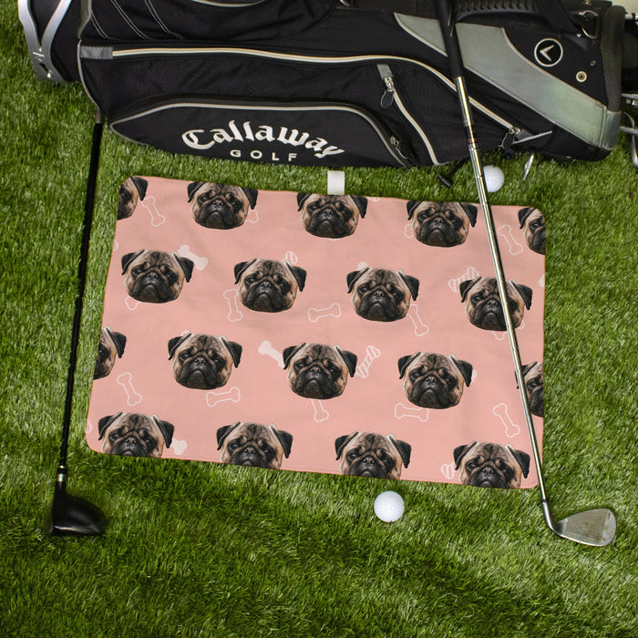 Golf towel with pug pattern on grass next to a Callaway golf bag and club