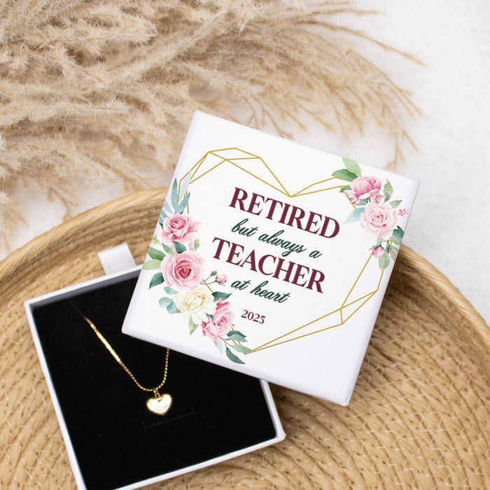 Jewelry box with a gold necklace and 'Retired but always a teacher at heart' message on a woven surface.