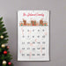 Personalized family name Christmas advent calendar with gingerbread houses on a gray wall.