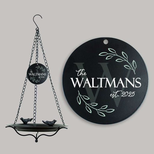 Round black bird bath sail with personalized last name and establishment year, hanging on a gray background.