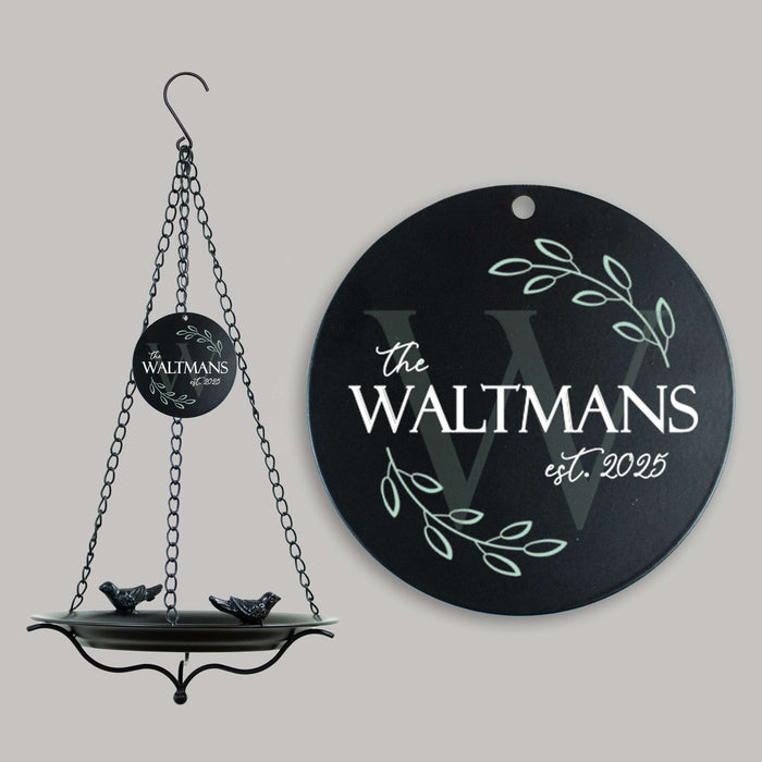 Round black bird bath sail with personalized last name and establishment year, hanging on a gray background.