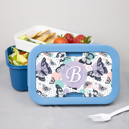 Bento box with butterfly design and monogram on a gray background