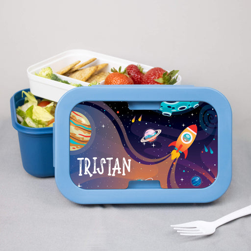 Space-themed lunch box with 'TRISTAN' printed on it, containing a meal and a fork.