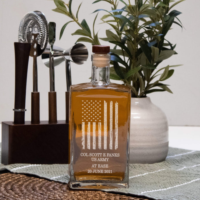 whiskey or bourbon decanter with american flag for military retirement in front of a bar tool set and plant