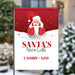 Christmas-themed garden flag with Santa Claus and 'Santa's Nice List' text, set against a blurred snowy outdoor background.