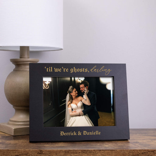 black wooden frame engraved with t'til we're ghosts darling and the couples names