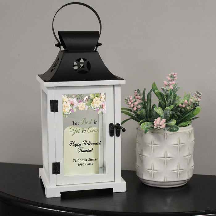 lantern with floral design for retirement gift on a black table beside a pink flower