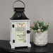 lantern with floral design for retirement gift on a black table beside a pink flower