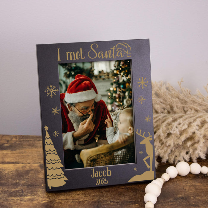Personalized photo frame with a picture of a child meeting Santa Claus, placed on a wooden surface.