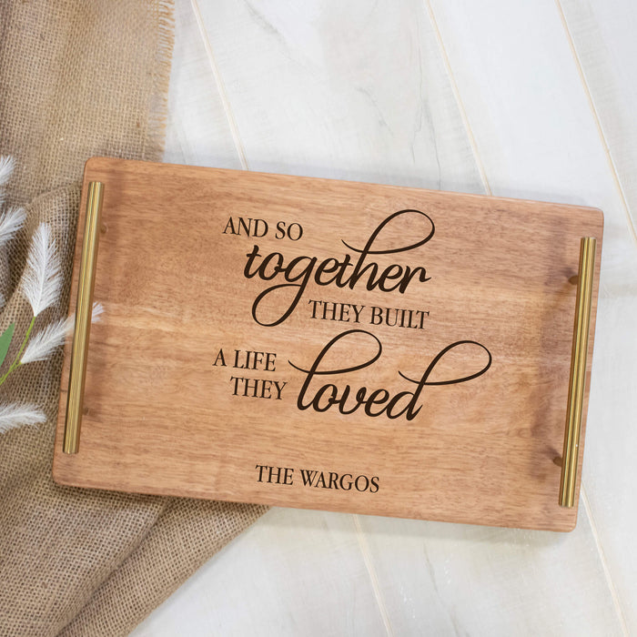 Wooden cutting board with engraved text and handles on a neutral background for couple gift
