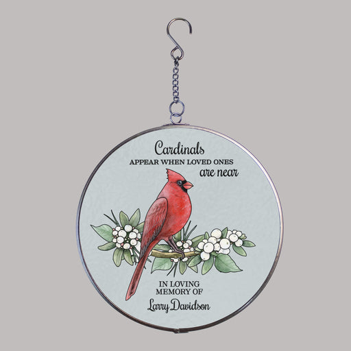 round acrylic suncatcher with a red cardinal sitting on a tree branch design in front of a gray background