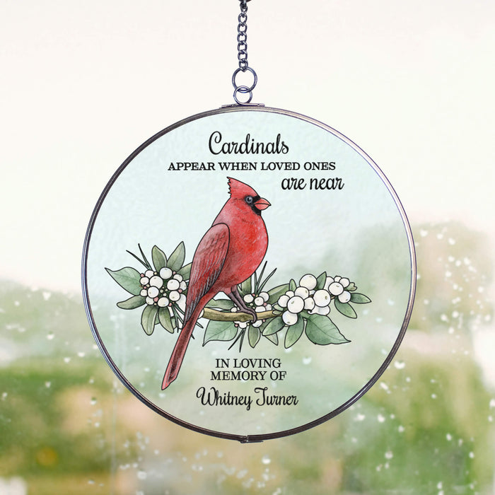 circular hanging suncatcher with memorial quote and red cardinal hung on a window with rain