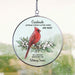 circular hanging suncatcher with memorial quote and red cardinal hung on a window with rain