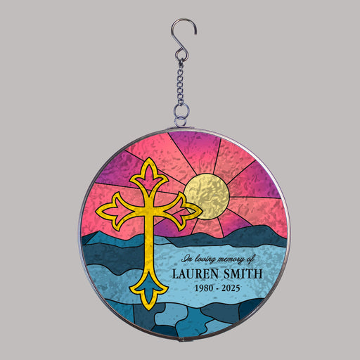 round suncatcher with cross in front of a sunset over the ocean design for memorial