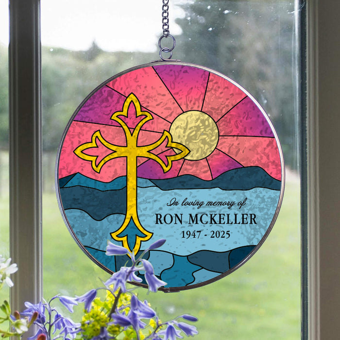 round suncatcher hanging in a window with a purple flower in front designed to look like a sunset over the ocean with a custom memorial message