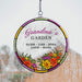 Round decorative hanging suncatcher with 'Grandma's Garden' and names, featuring colorful flowers on a window with rain