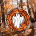 Halloween-themed stained glass window hanging light catcher with a ghost design against an autumn tree background.
