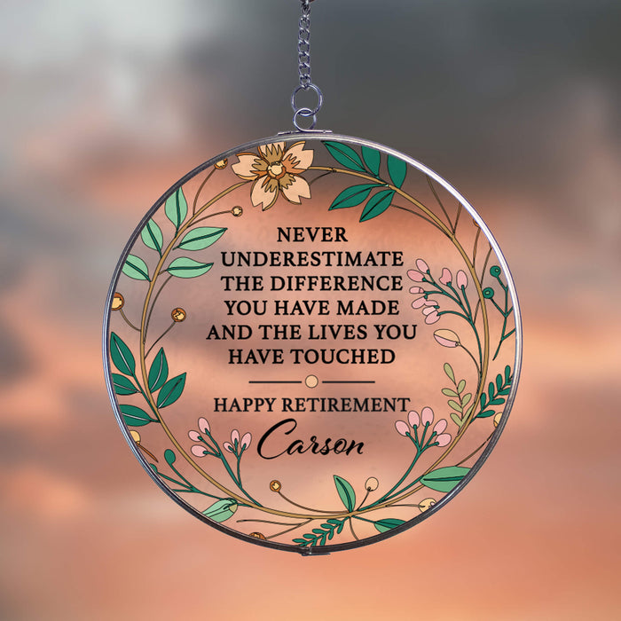 Round decorative suncatcher plaque with floral design and retirement message on a blurred peach colored background