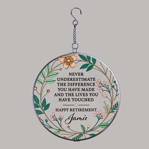 Round decorative hanging suncatcher with floral design and retirement message on a gray background