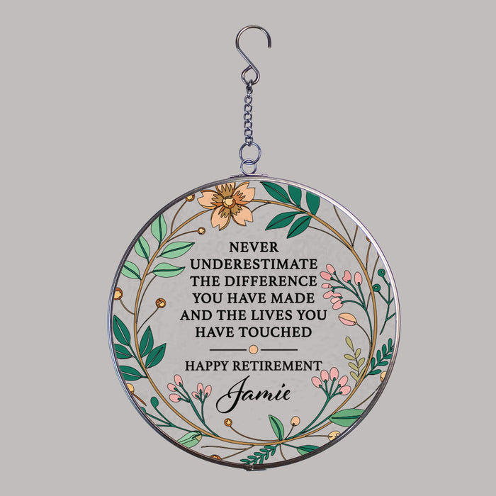 Round decorative hanging suncatcher with floral design and retirement message on a gray background