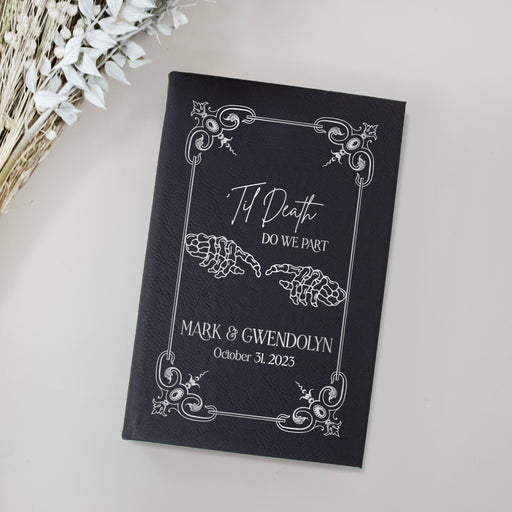 black journal with silver engraving that reads til death do we part with names and event date