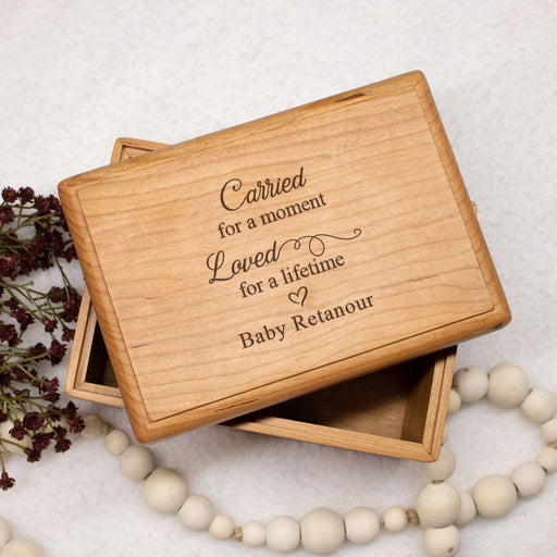 Wooden baby memory box with engraved text on a light background