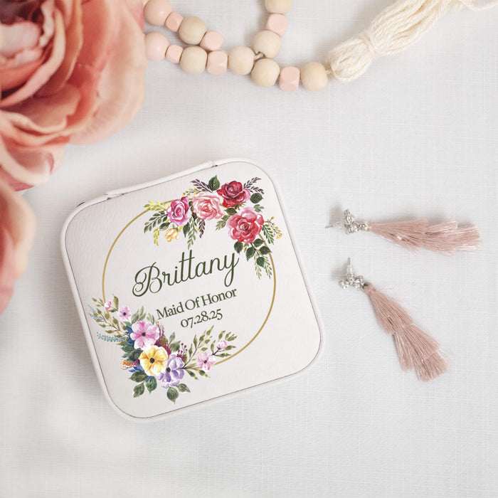 Personalized maid of honor jewelry box with floral design and text, accompanied by pink roses and tassel earrings.