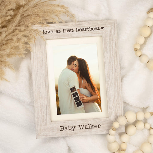 love at first heartbeat picture frame on white blanket with neutral decor